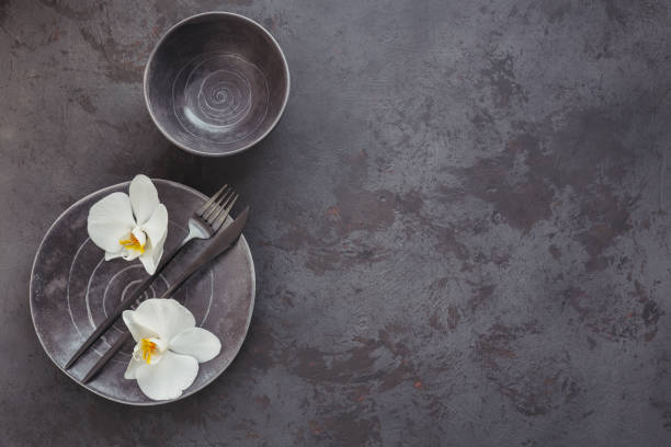 istock Elegance table setting with knitted grey napkin, cutlery, ceramic plates, glasses and white orchid flowers 1187399598
