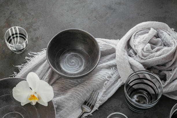 istock Elegance table setting with knitted grey napkin, cutlery, ceramic plates, glasses and white orchid flowers 1187399637
