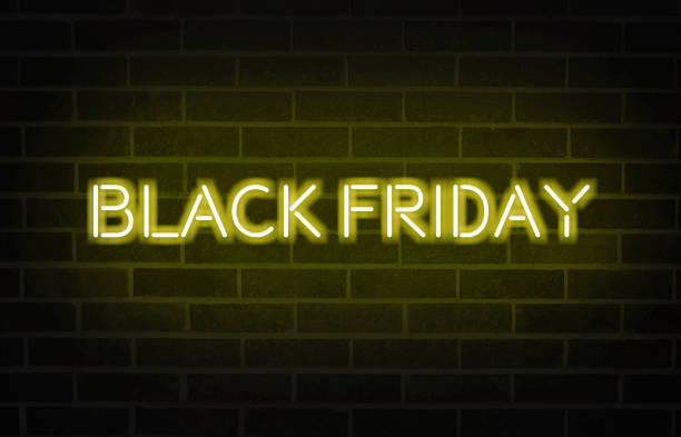 istock Black Friday text with bright yellow neon font on blacked brick wall 1187400523