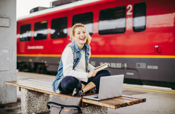 jeune femme s'asseyant à la gare de chemin de fer, travaillant sur l'ordinateur portatif - 7947 photos et images de collection