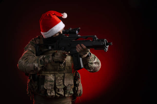 a man in a military uniform with a gun and a santa claus hat - airsoft gun imagens e fotografias de stock