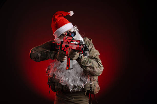 ein mann in militäruniform mit pistole und weihnachtsmannhut - airsoft gun stock-fotos und bilder