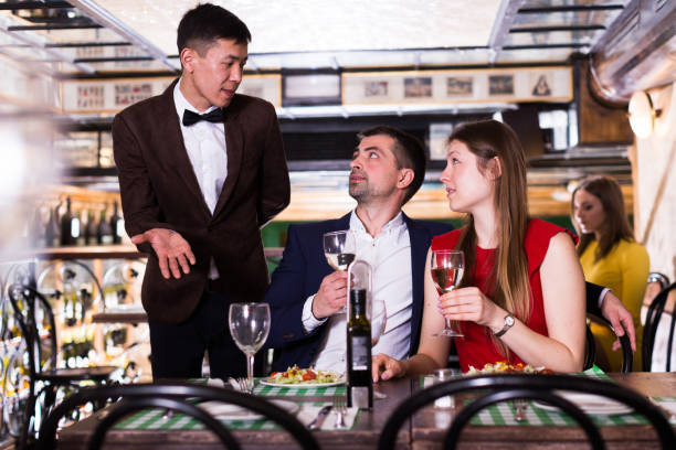 istock Male administrator is asking about service from smiling couple who is drinking wine in restaurant. 1187404373