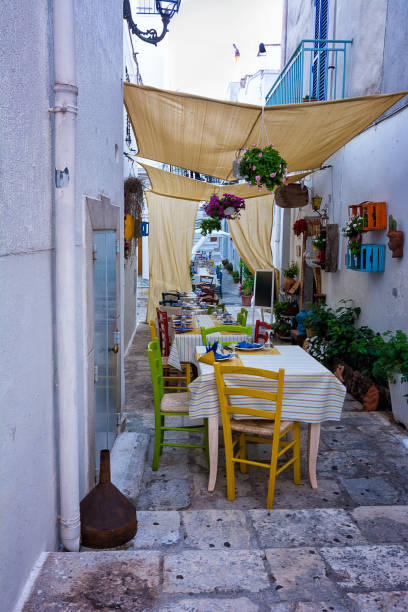 mesas de restaurante para la cena en un callejón de ceglie messapica en puglia (italia) - brindisi fotografías e imágenes de stock