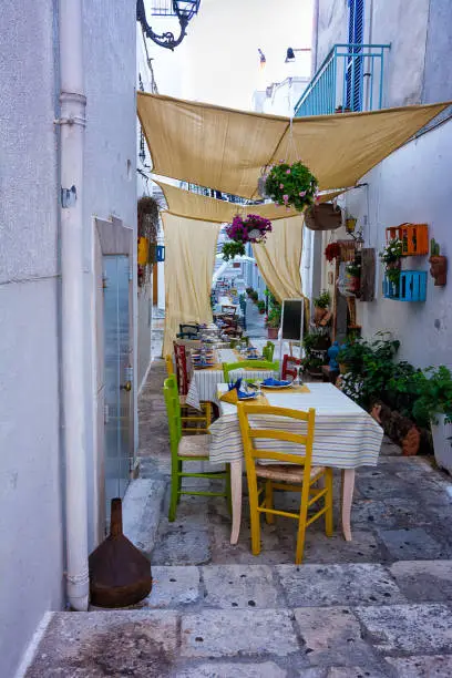 Restaurant tables set for dinner in an alleyway of Ceglie messapica in Puglia (Italy)