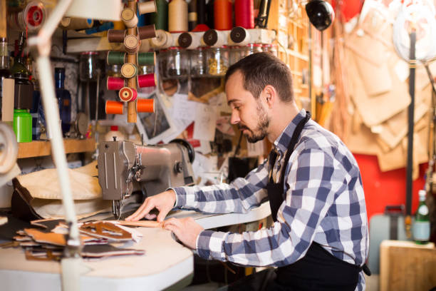 istock male worker sewing stitches on belt in leather workshop 1187407489
