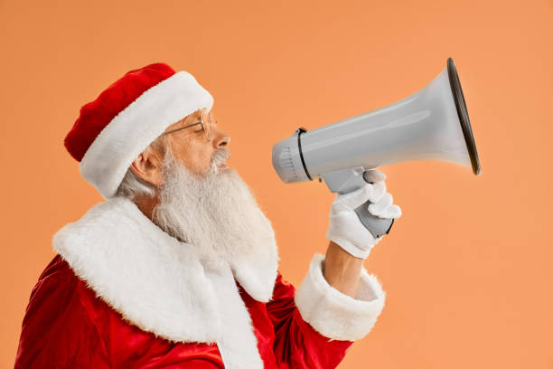 istock Happy mature Santa Claus speaking in megaphone in studio 1187408947