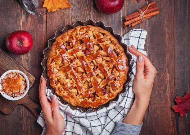 istock Woman's hands putting fresh baked apple pie on wooden table 1187411428