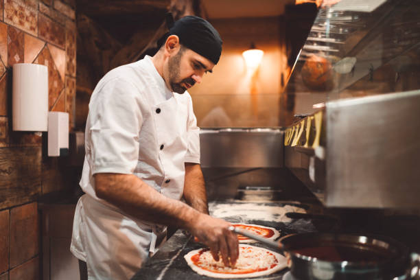 istock Pizza maker topping the pizza with mozzarella cheese 1187411959