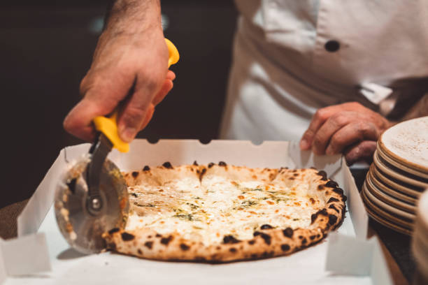 istock Man hand cutting freshly baked pizza with a pizza cutter 1187411974