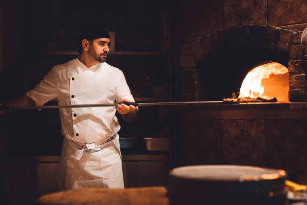 istock Pizza maker taking pizza out of the oven with a peel 1187411987