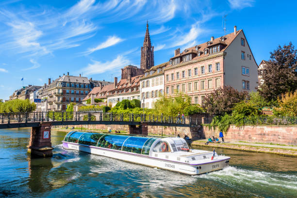 una barca turistica sta navigando sul fiume ill intorno al quartiere storico di strasburgo, in francia. - strasbourg france cathedrale notre dame cathedral europe foto e immagini stock