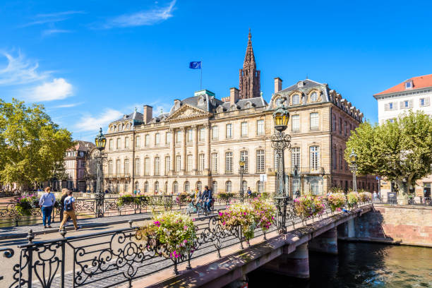 fachada principal do palácio de rohan que enfrenta o rio ill e a ponte de sainte-madeleine com o campanário da catedral de notre-dame em strasbourg, france. - strasbourg cathedral - fotografias e filmes do acervo