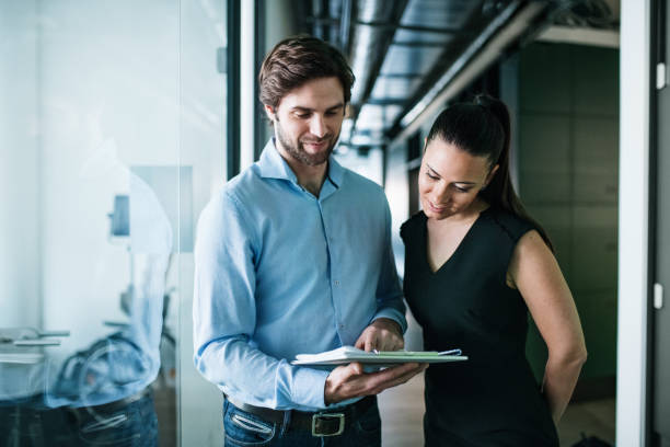 istock Young businesspeople with clipboard in an office, working. 1187421592