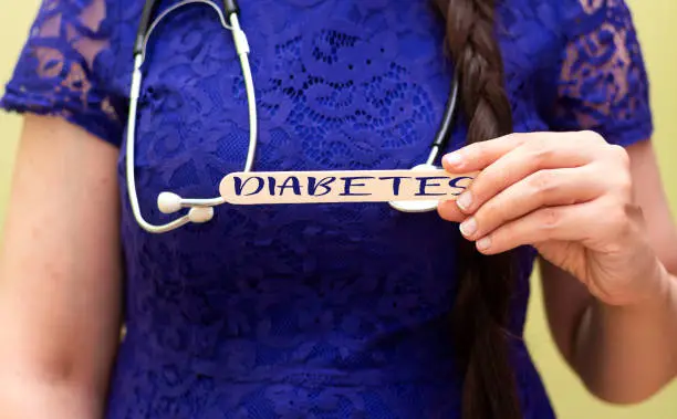 Photo of woman holding  wooden spatula with diabetes text and wearing stethoscope