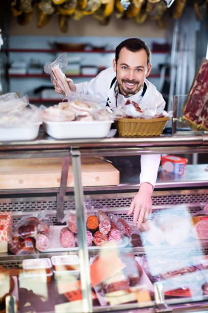 istock Smiling man seller showing sausages 1187422184