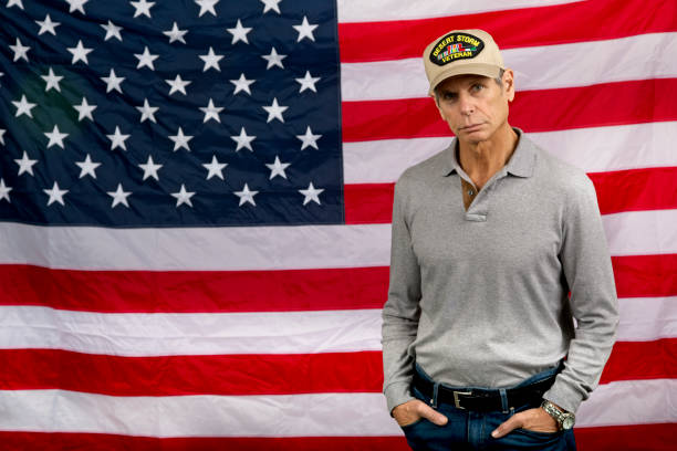 istock Gulf War Veteran with serious look facing camera, American Flag background. 1187423015