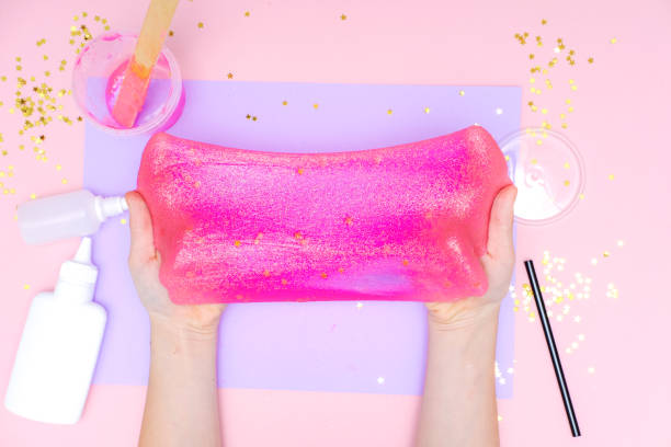 How to make slime at home. Children art project. DIY concept. Kids hands making slime toy on pink. Step by step photo instruction. Step 12 stock photo