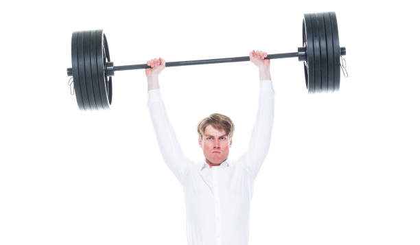 One person / waist up of 20-29 years old adult handsome people caucasian young men / male sportsperson / business person / businessman exercising at the health club in the gym wearing button down shirt / shirt / pants / business casual / smart casual who is serious / confidence / concentration and being active with barbell / weightlifting / weight training / weights / cross training / body building / sports training / heavy una persona / cintura para arriba de 20-29 años de edad adulto guapos hombres jóvenes caucásicos / deportista masculino / hombre de negocios / hombre de negocios haciendo ejercicio en el club de salud en el gimnasio usando botón hacia abajo camisa / ca