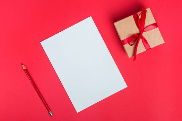 istock Blank paper card, giftbox with red bow ans pencil on red background 1187423651