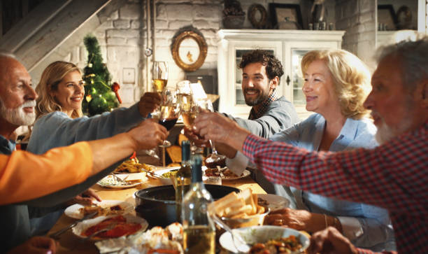 Family having Thanksgiving dinner. Closeup of multi generation family enjoying Thanksgiving dinner at a vacation house. They are having a toast with red and white wine. multi generation family christmas stock pictures, royalty-free photos & images