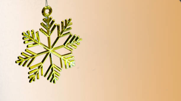 istock One golden plastic snowflake decoration on a golden background. 1187427949