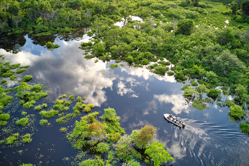 Odzala National Park, Republic of Congo - May 19, 2019: Aerial view of a tourist motor boat on a jungle river in the rainforest of the Congo Basin. Odzala National Park, Republic of Congo.