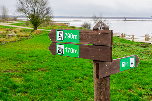 wooden direction indicator in the park with pictograms and distance signs in meters
