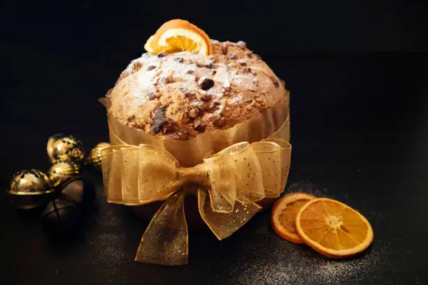 Panettone gourmet on black background. Traditional Christmas gift. Fruitcake with oranges. Easter cake.