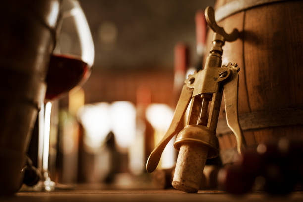 Wine tasting in the cellar, wooden barrel and vintage corkscrew in the foreground, wine culture concept