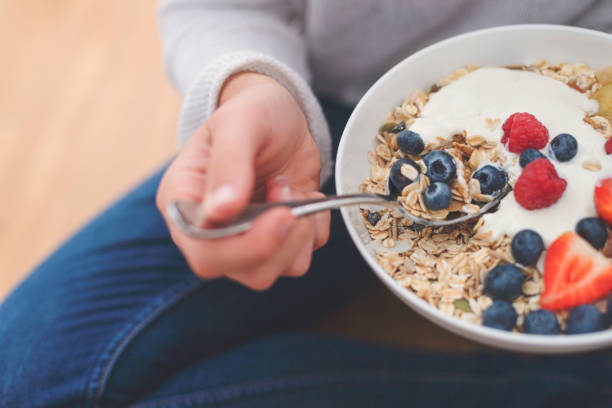 Woman Eating healthy breakfast bowl. Woman Eating healthy breakfast bowl. It includes strawberries, blueberries, kiwifruit, granola, muesli  and yoghurt. Clean eating, dieting, detox, vegetarian food concept. Shot from above granola photos stock pictures, royalty-free photos & images