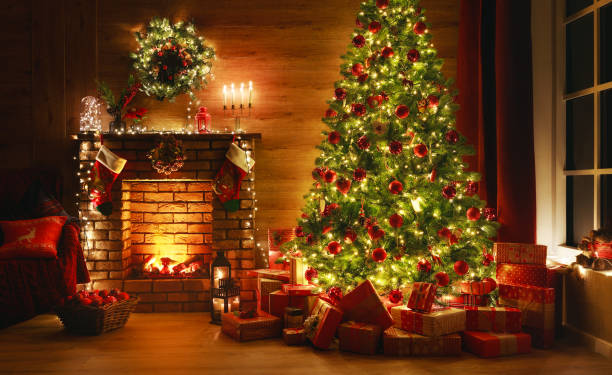 インテリアクリスマス。魔法の輝く木、暖炉、暗闇の中の贈り物 - 伝統 写真 ストックフォトと画像