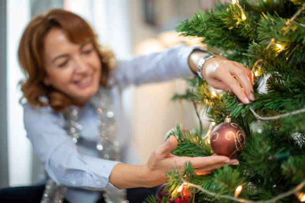 istock Happy ginger woman decorating Christmas tree 1187457030