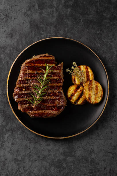 istock Medium Ribeye steak with potatoes on black plate 1187461277