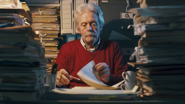 istock Senior office clerk surrounded by piles of paperwork 1187461337
