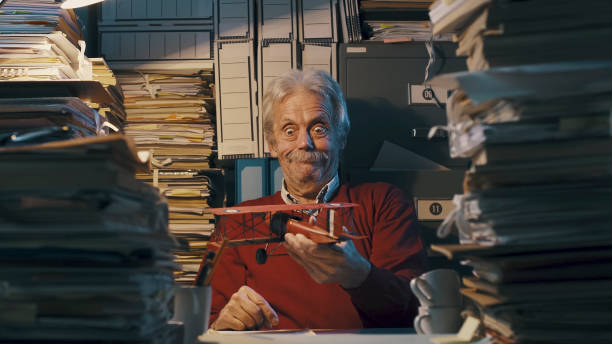 istock Senior office worker with vintage toy plane 1187461410