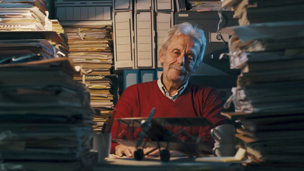 istock Senior office worker with vintage toy plane 1187461434