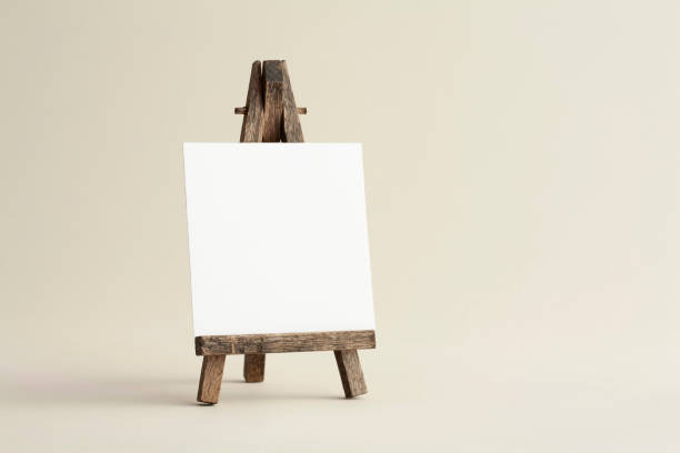 istock Square empty white business card mockup with wooden easel on bone coloured background. 1187469786