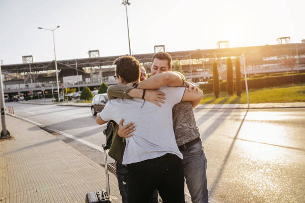 Welcome hug Two young men meeting friend on airport and give him big hug to welcome airport hug stock pictures, royalty-free photos & images