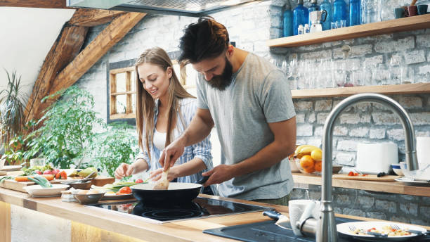 istock Young couple making dinner together at home 1187483269