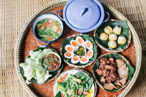 Photo of Set of local food at Na Ton Chan homestay,fried fish with tomato,corn,cucumber and boil vegetable  Si Satchanalai district, Sukhothai Province ,Thailand.on Khantoke traditionally meal set popular