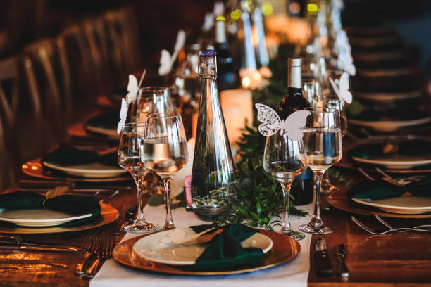 istock Dining table setting. Banquet or dinner background in a rustic atmosphere. Vintage decoration of reception table. Elegant arrangement of the holiday tableware. Wine glasses, plates, forks and green briefcases for event. 1187504545