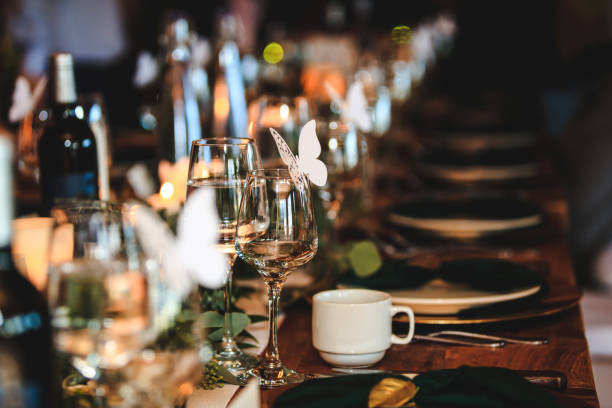 istock Banquet or holiday background in a rustic atmosphere.  Dinner table setting. Vintage decoration of reception table. Elegant arrangement of the holiday tableware. Wine glasses, plates, forks and green briefcases for event. 1187504546