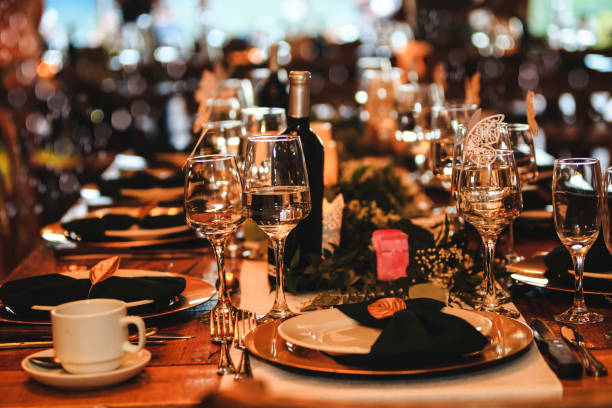 istock Beautiful dinner table setting. Vintage decoration of reception table. Elegant arrangement of the holiday tableware. Wine glasses, plates, forks and green briefcases for event celebration. Banquet background in a rustic atmosphere. 1187504548