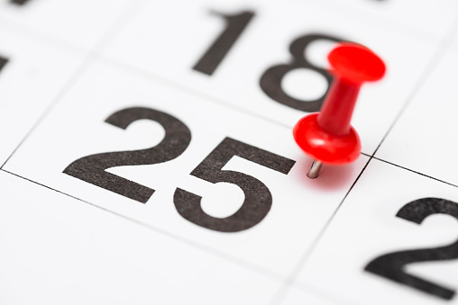 Pin on the date number 25. The twenty fifth day of the month is marked with a red thumbtack. Pin on calendar.