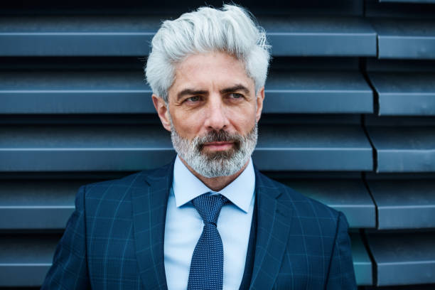 istock A mature businessman standing outdoors against dark background. 1187532635