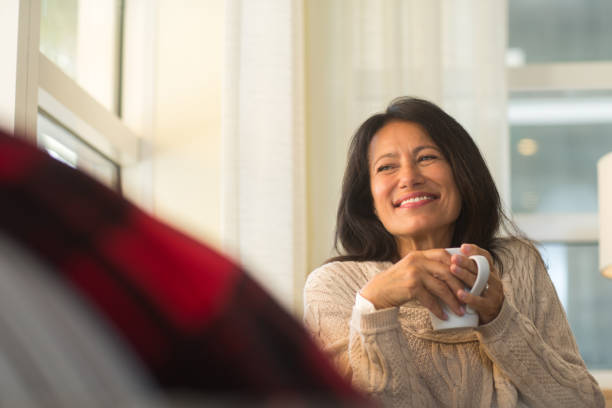 istock Hispanic woman sitting on the sofa drinking coffee. 1187534634