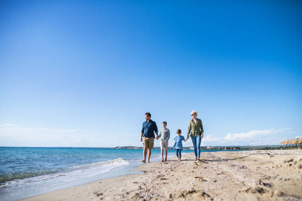 istock Young family with two small children walking outdoors on beach. 1187535759