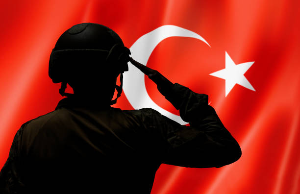 Turkish soldier saluting to Turkish flag