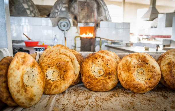 Handmade Lepeshka Traditional Uzbek Bread Uzbekistan Tashkent Non Handmade Traditional Lepeshka (Lepyoshka) Bread - Tashkent Non Flatbread in bakery close to Tashkent Bazaar. Uzbekistan is famous for their individual hand-made bakery and Lavash Bread Culture. Fired Open Tandoor (Tandyr) Oven in the background, Selective Focus. Tashkent, Uzbekistan, Central Asia. tashkent stock pictures, royalty-free photos & images